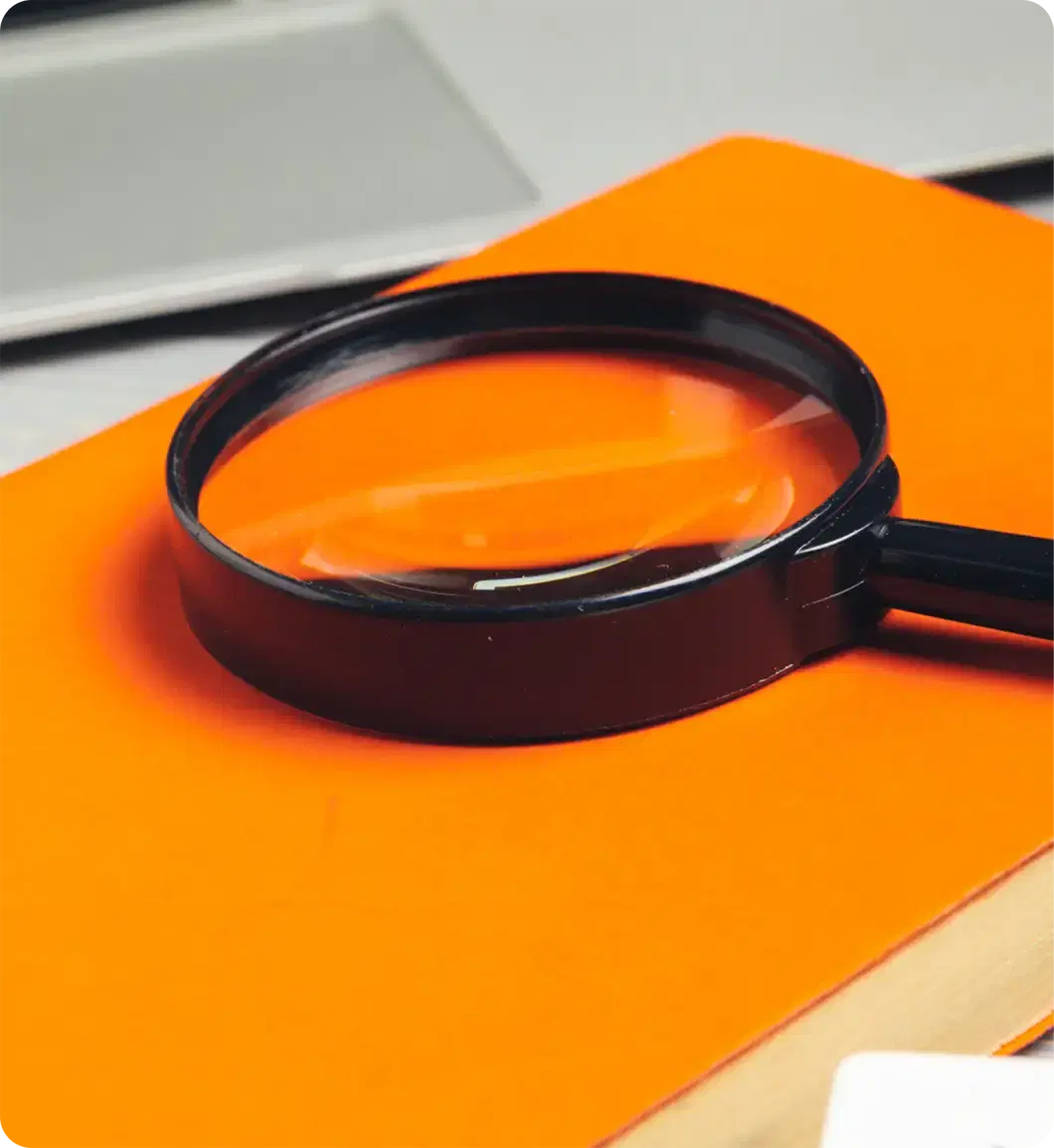 A magnifying glass resting on an orange folder