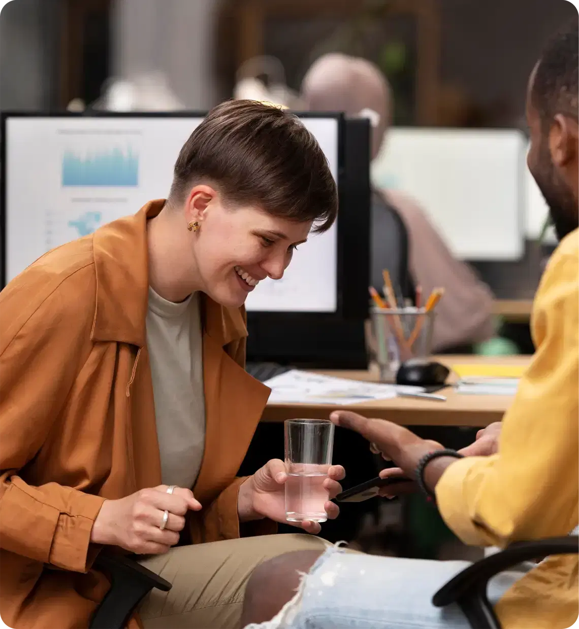 Two colleagues laughing together at a desk