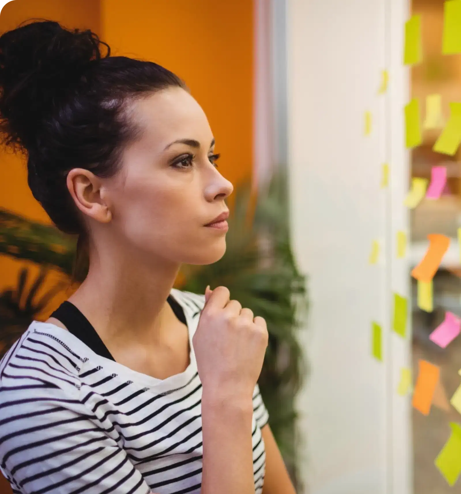 A woman thinking in front of a wall of sticky notes